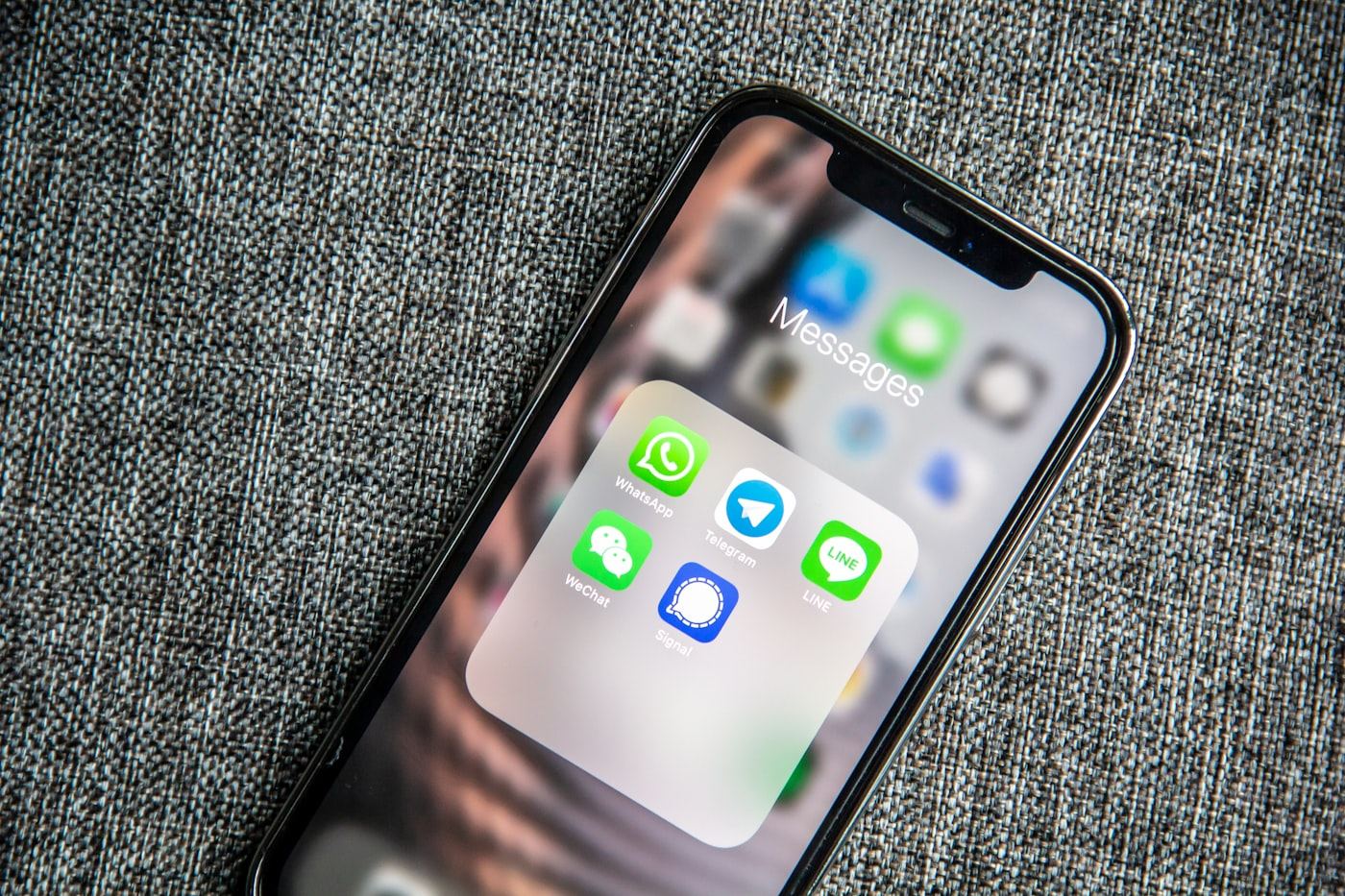 A hand holding a smartphone with a chat conversation open — an admissions query replied to within seconds